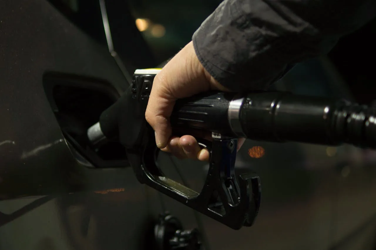 Person holding a fuel pump nozzle while refuelling a car, representing rising fuel prices and their impact on moving costs