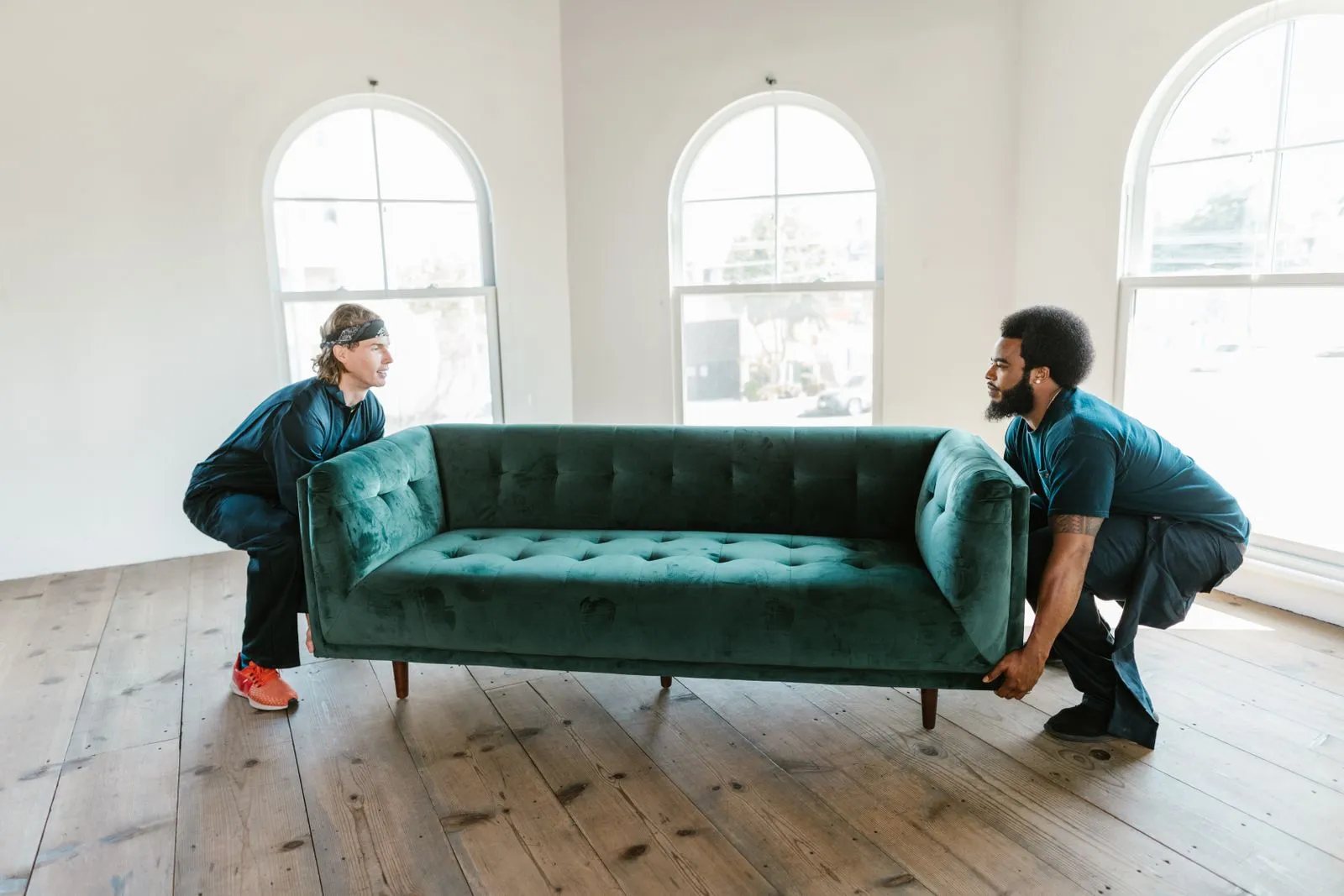Professional removalists carefully carrying a sofa, the kind of insured handling that limits damage during a move