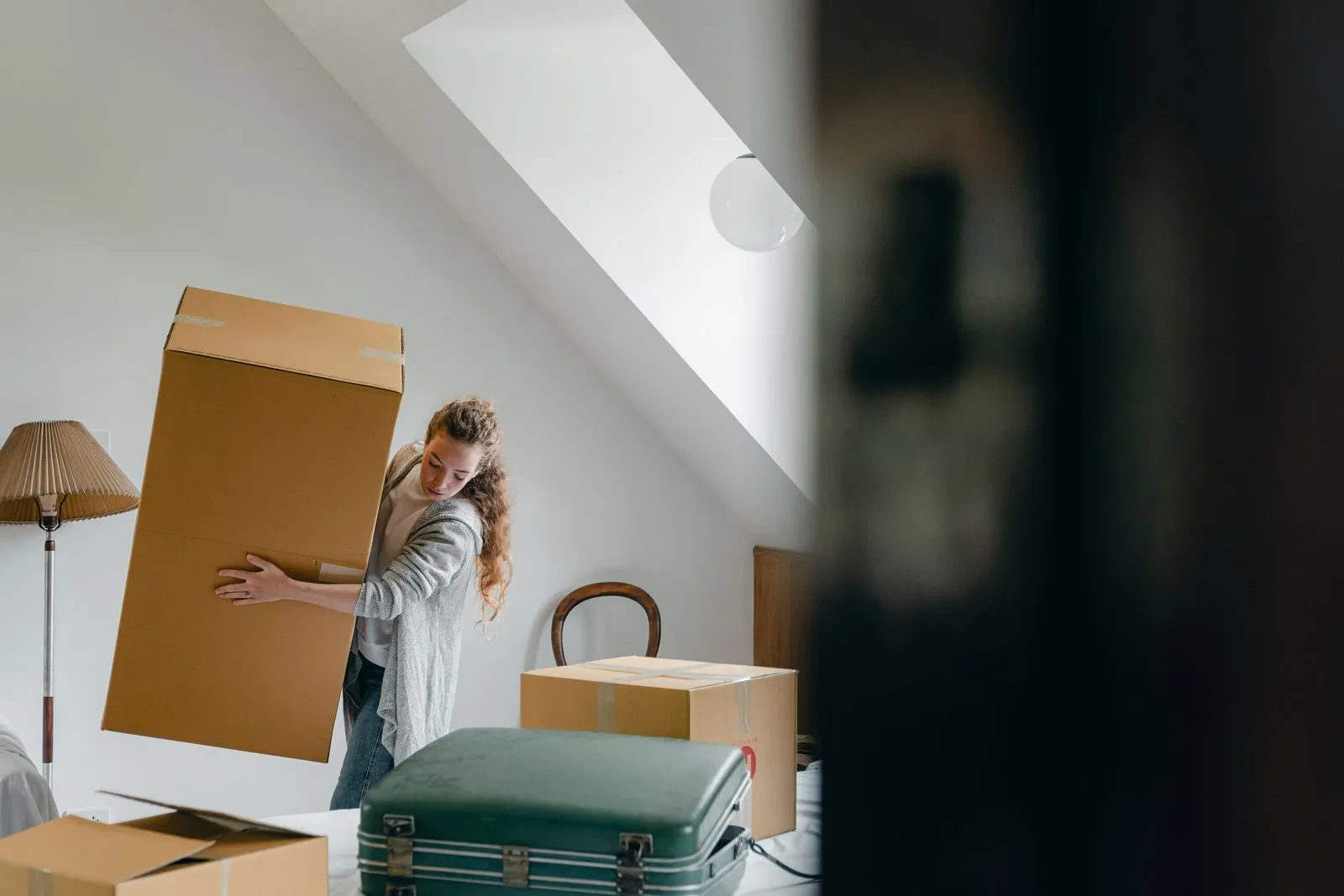 A woman carrying boxes into a new home where electricity, gas and internet need connecting